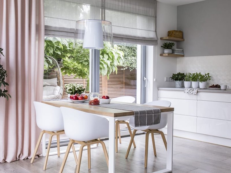 white table and chairs in a kitchen with white cabinets, big window and light gray hardwood floor from John's Flooring in Union, MO