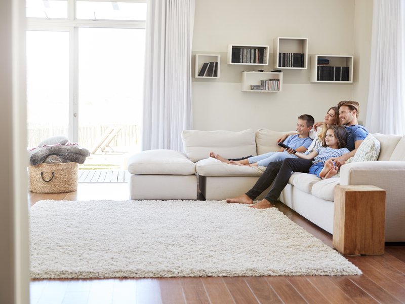 white couch and big smart tv on the wall in living room with brown laminate floor from John's Flooring in Union, MO
