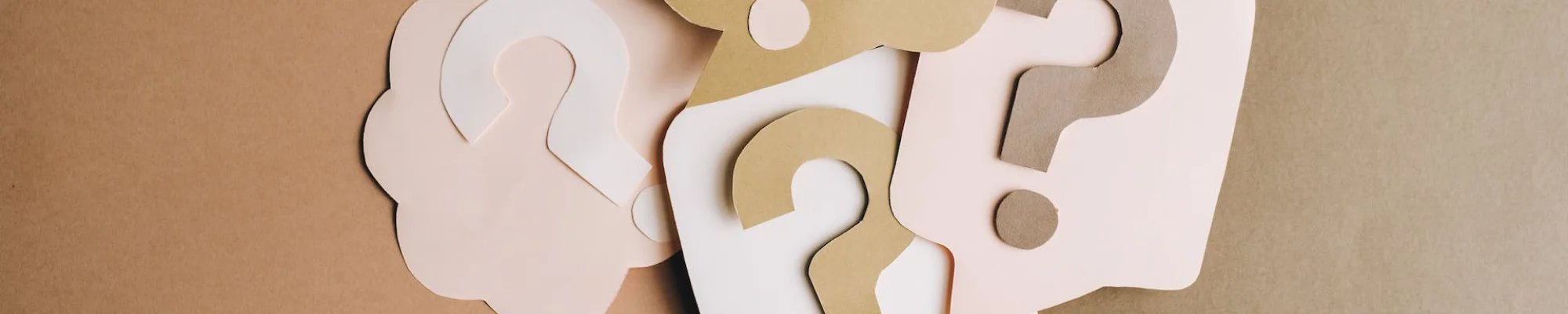 Question marks on beige and pink paper